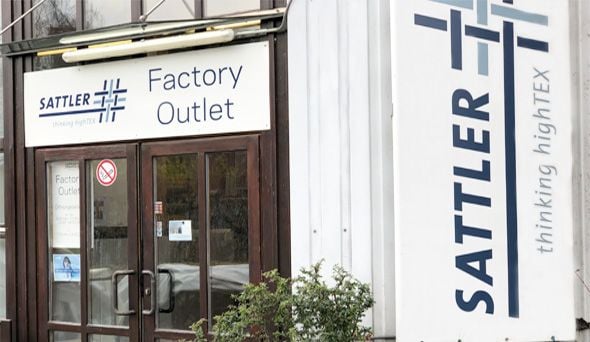 Eingang des SATTLER Factory Outlet mit dem Schriftzug „Factory Outlet“ über der Tür und „Sattler – thinking highTEX“.
