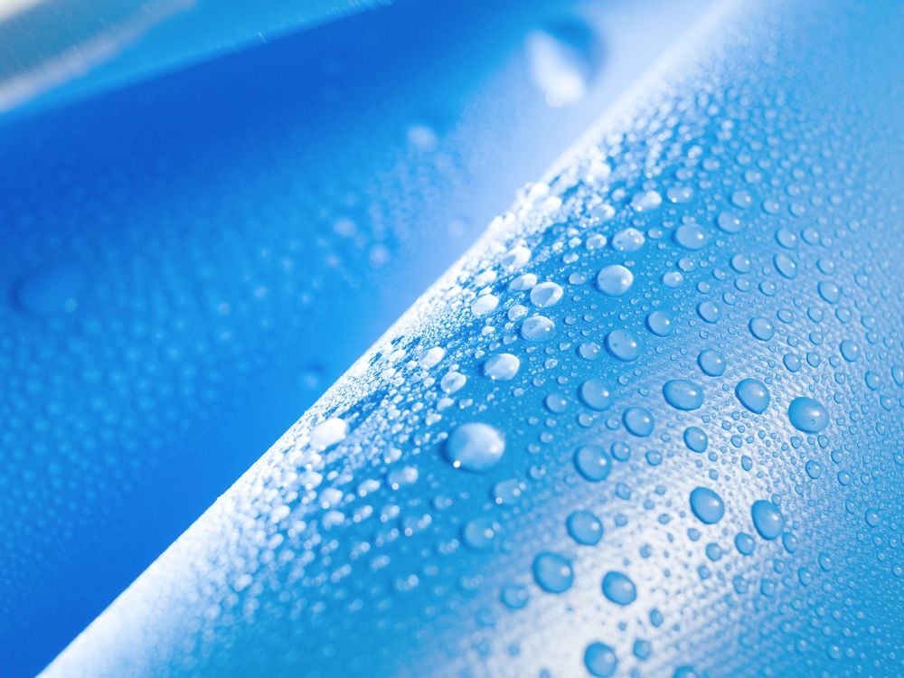 Blaue SATTLER-Membran mit Wassertropfen – Originalaufnahme technischer Textilien