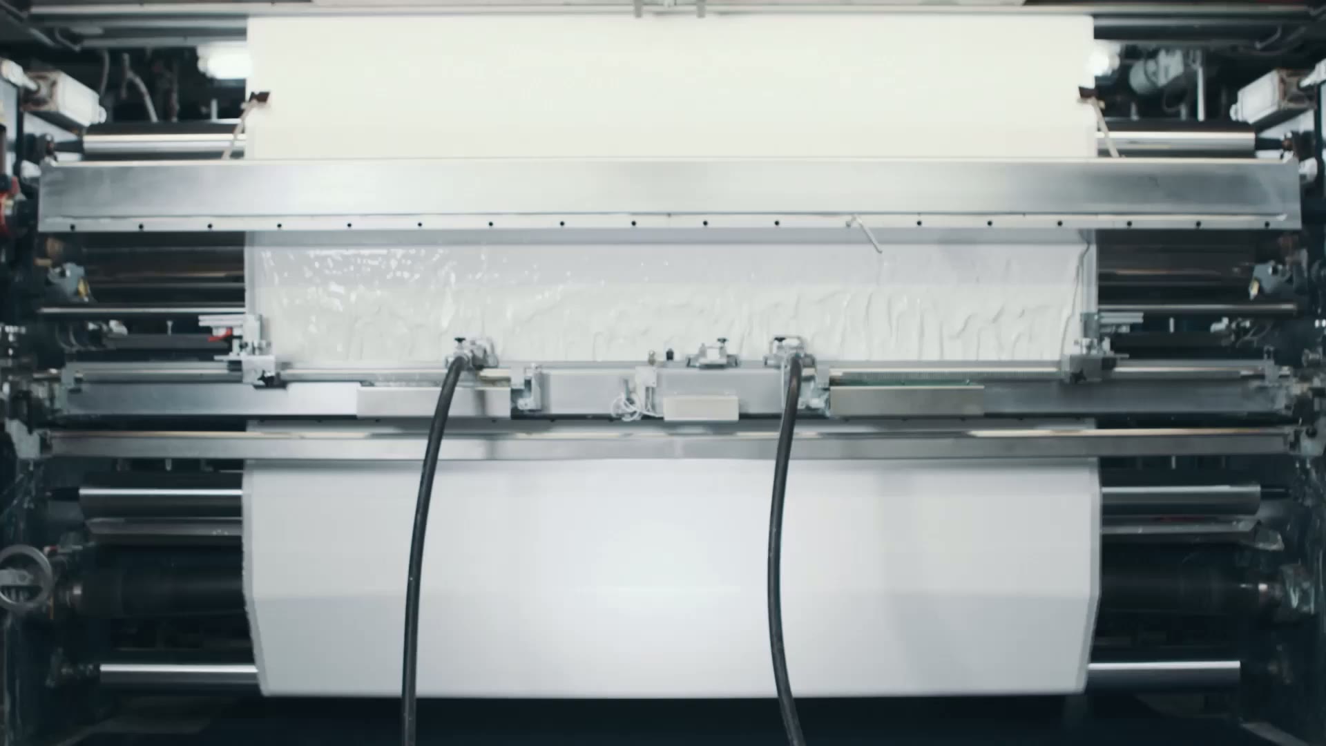 Weißes Gewebe läuft durch die Beschichtungsanlage – Standbild aus dem Sattler Unternehmensfilm.