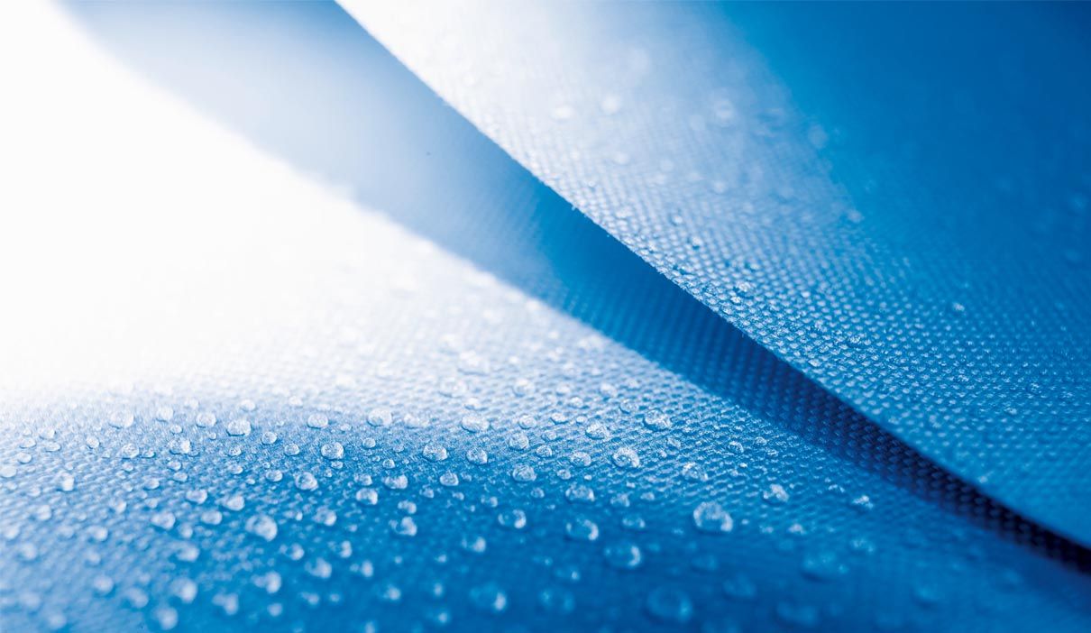 Blaue Membranoberfläche mit abperlenden Wassertropfen.